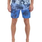 Blue leaf-patterned swim shorts worn by a person on a white background