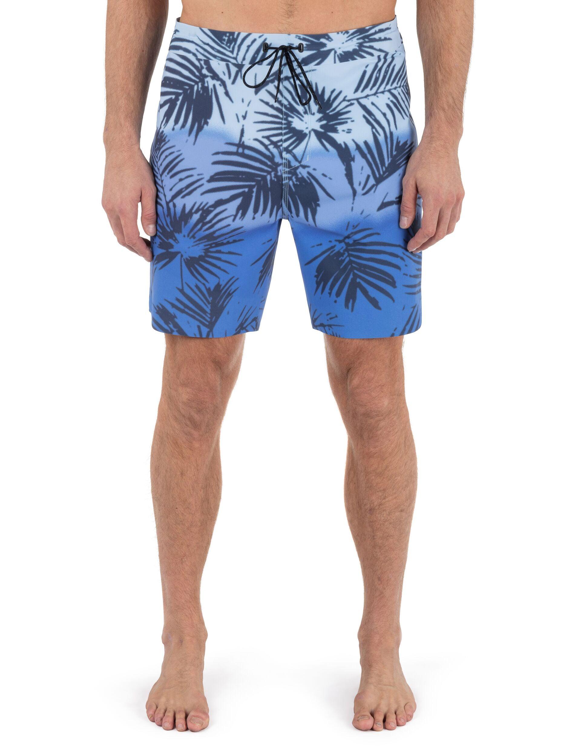 Blue leaf-patterned swim shorts worn by a person on a white background