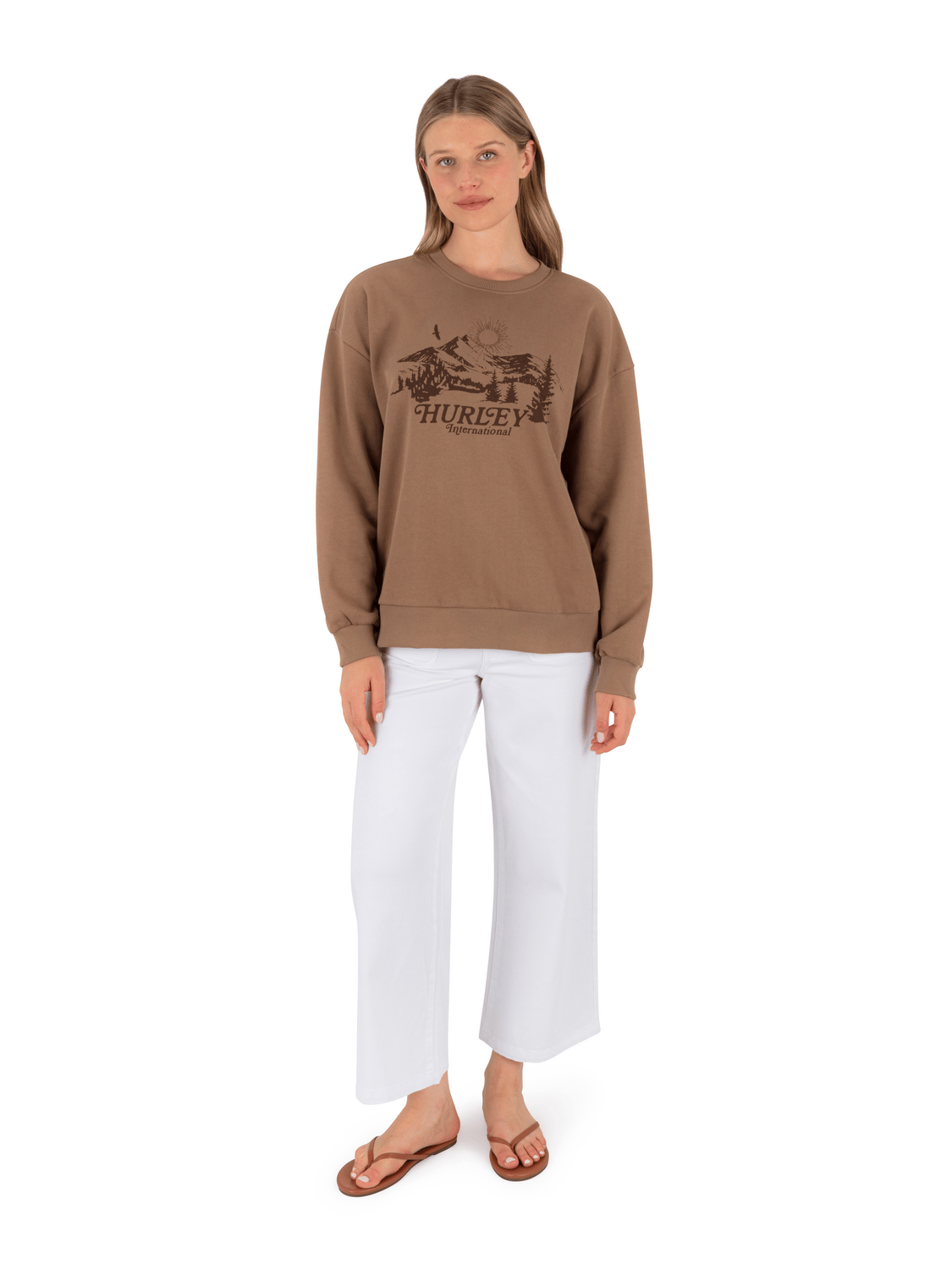 Woman wearing a brown sweatshirt with a logo and text, standing against a white background